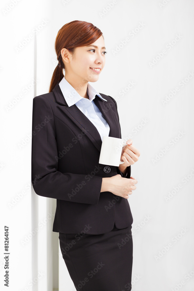 young businesswoman leaning against white wall in office young businesswoman leaning against white wall in office