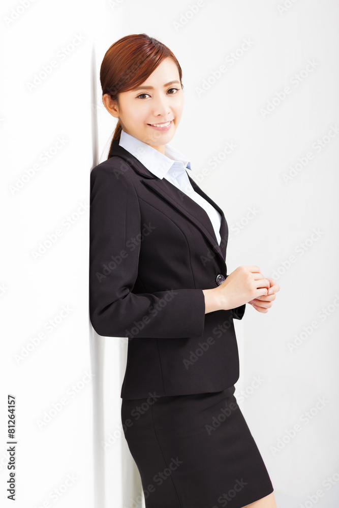 young businesswoman leaning against white wall in office young businesswoman leaning against white wall in office
