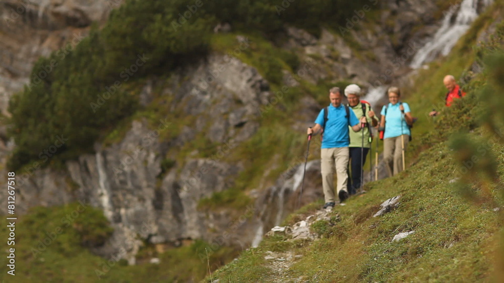 hikers walking down hill near waterfall hikers walking down hill near waterfall