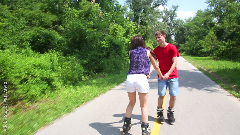 Young woman and man rollerblading on a sunny day in park, holding hands. Young woman and man rollerblading on a sunny day in park, holding hands.