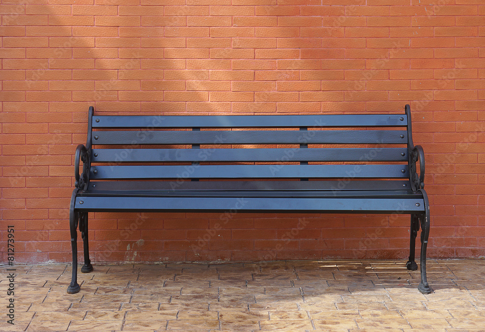 Black painted timber bench with brick wall background Black painted timber bench with brick wall background