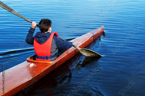 The boy rowing in a kayak on the river © Natalija Sirokova