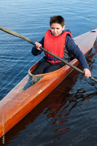 The boy rowing in a kayak on the river