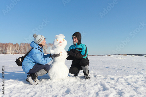 The man and woman building a snowman