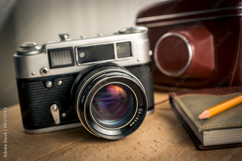 Closeup shot of classic film camera and notebook on wooden desk