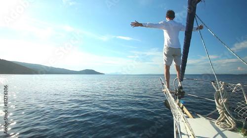 Man standing on the bow of sailing boat on Mediterranean sea.