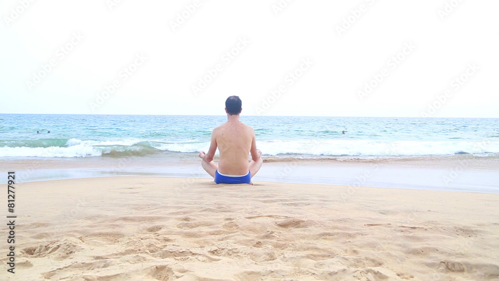 Man meditating on sandy beach in the tropics Man meditating on sandy beach in the tropics