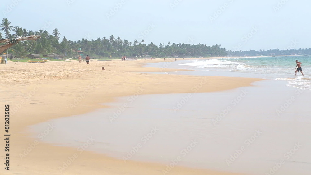 HIKKADUWA, SRI LANKA - FEBRUARY 2014: Man coming out of sea on sandy beach. HIKKADUWA, SRI LANKA - FEBRUARY 2014: Man coming out of sea on sandy beach.