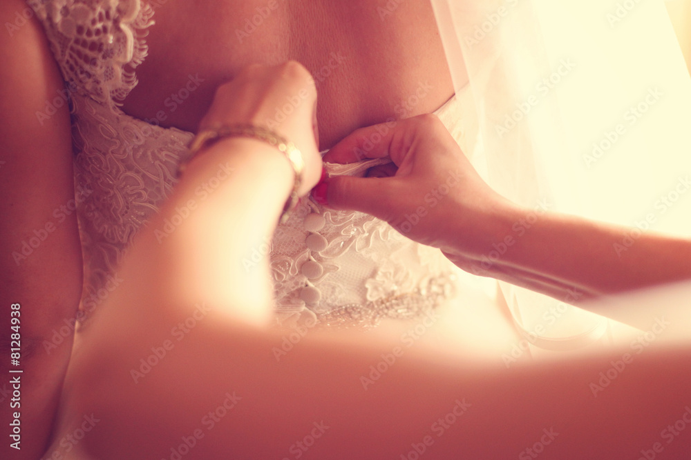 Hands of bridesmaid helping the bride with wedding dress Hands of bridesmaid helping the bride with wedding dress