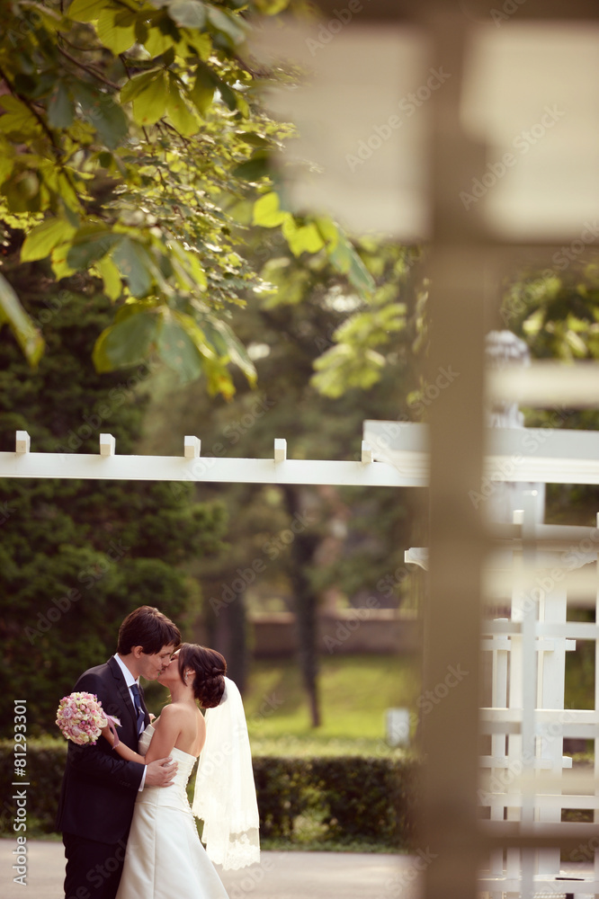 Naklejka premium Bride and groom kissing in the park