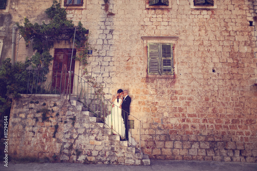 Bride and groom on stairs near a house © hreniuca