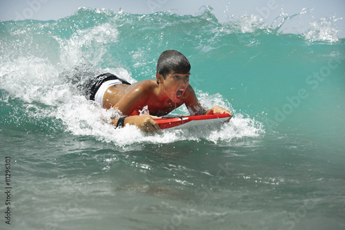Teenager catching a wave, a surfboard © fresnel6