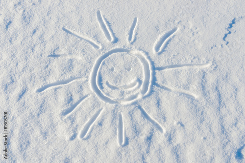 smiling sun drawn on the surface of the snow in the winter