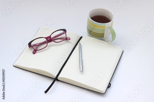 Blank open notebook with cup of tea and pen