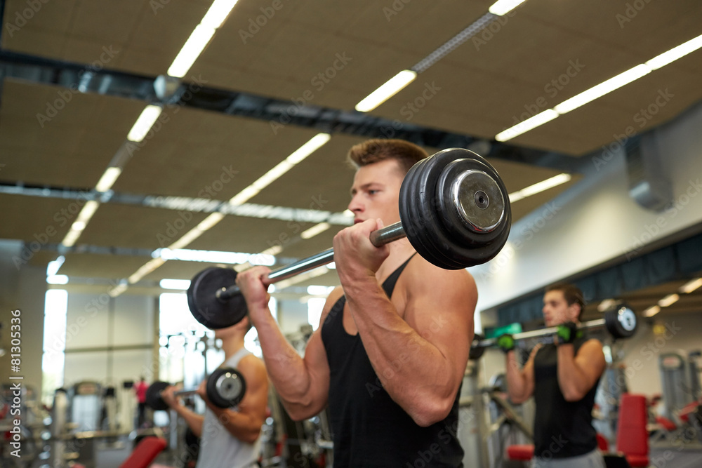 young men flexing muscles with barbells in gym