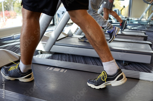close up of men legs walking on treadmills in gym
