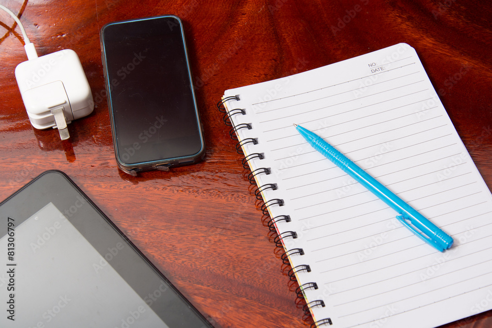 Tablet with notebook on wooden table and pen Tablet with notebook on wooden table and pen