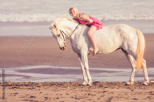Young happy woman lies and hugs the horse