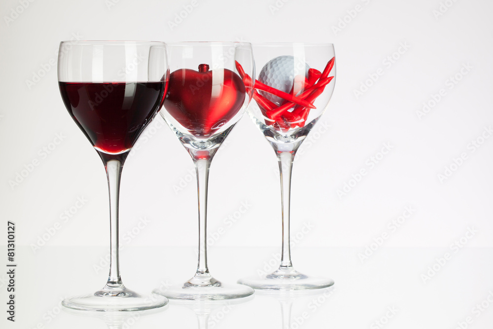 Wine glasses with red wine, heart and golf ball