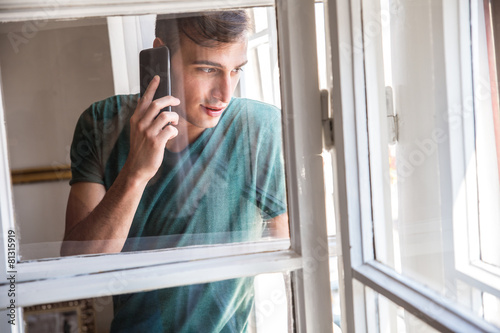 Man standing by the window and using smart phone