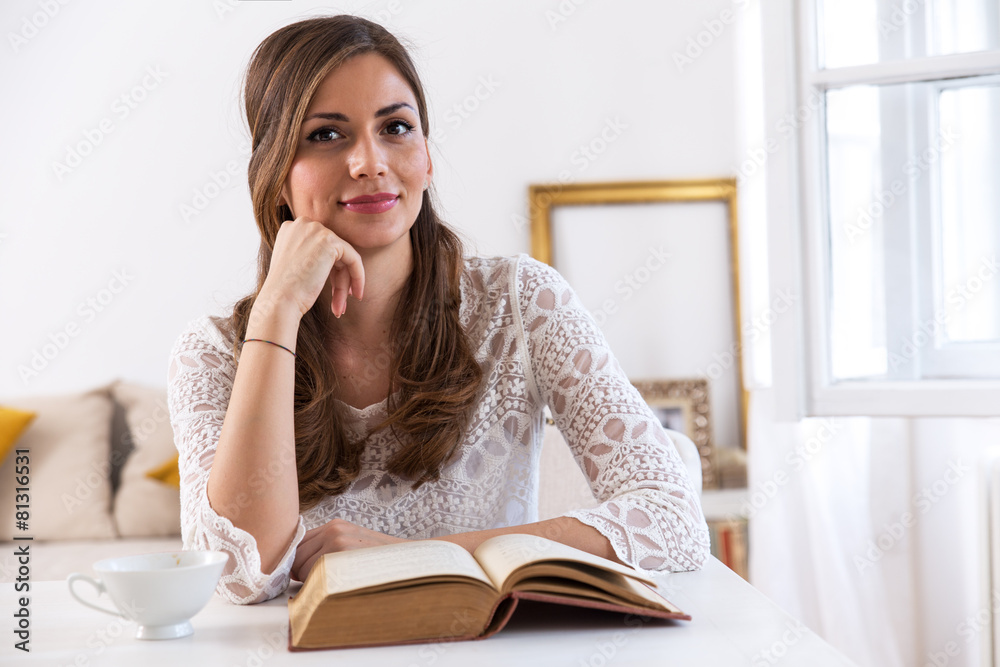 Charming woman sitting by wooden table and reading book Charming woman sitting by wooden table and reading book
