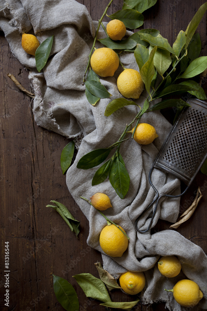 group of fresh lemons with leaves on wooden table with grater