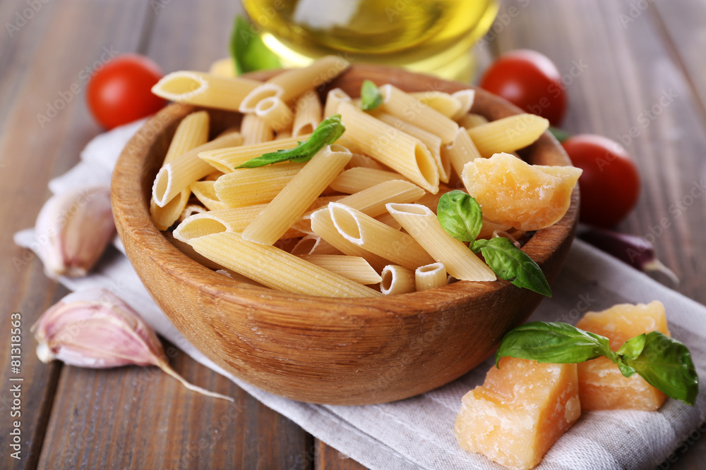 Raw pasta in bowl with cheese and vegetables on table close up Raw pasta in bowl with cheese and vegetables on table close up