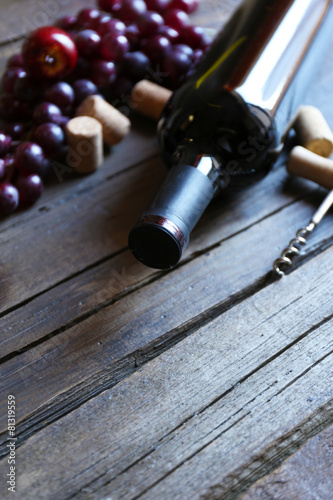 Bottle of red wine with grape on wooden background