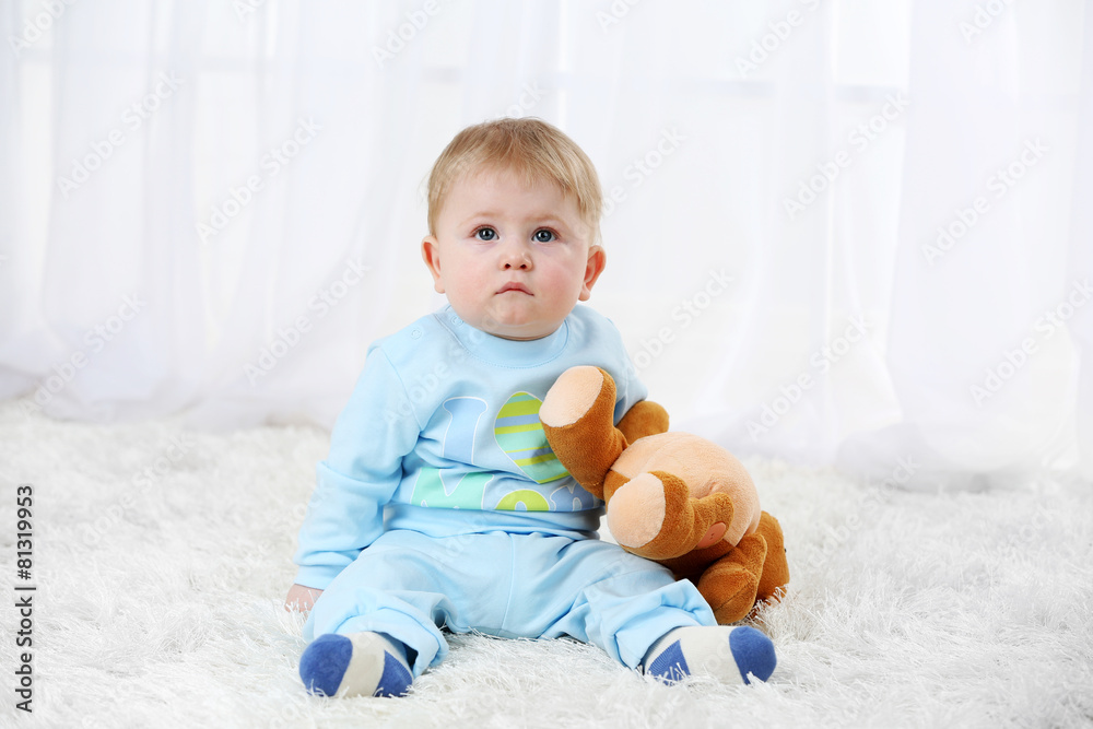 Cute baby boy with teddy bear on carpet, on light background Cute baby boy with teddy bear on carpet, on light background
