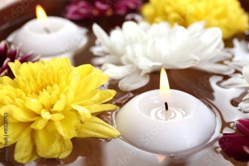 Bowl of spa water with flowers and candles, closeup