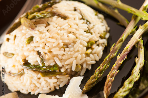 Rice with wild asparagus on a blavk plate with fork served on a