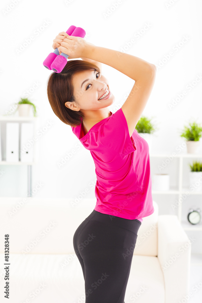 happy young woman exercising with dumbbells in living room happy young woman exercising with dumbbells in living room