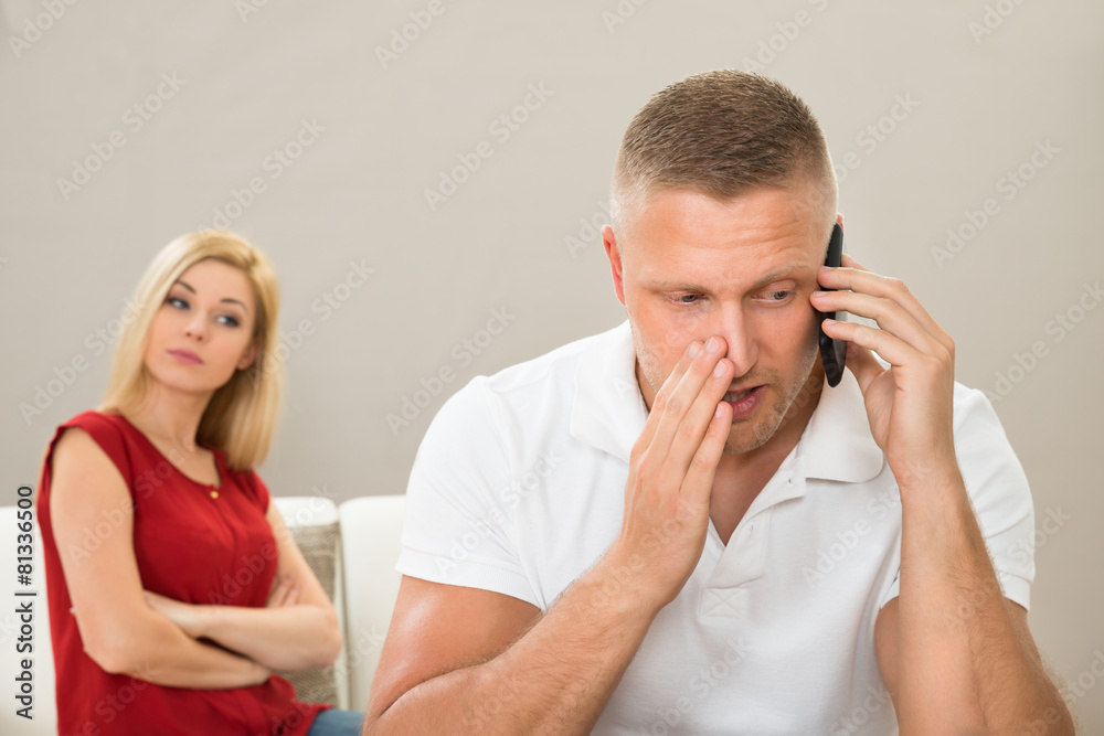 Wife Looking At Husband Talking On Mobile Phone Wife Looking At Husband Talking On Mobile Phone