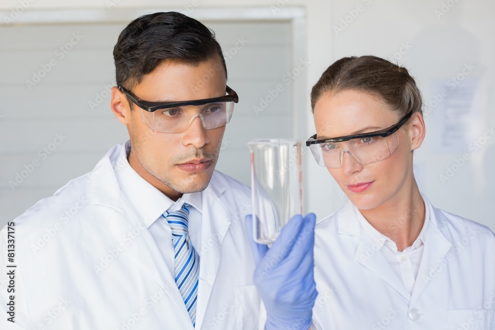 Concentrated scientists looking at beaker Concentrated scientists looking at beaker
