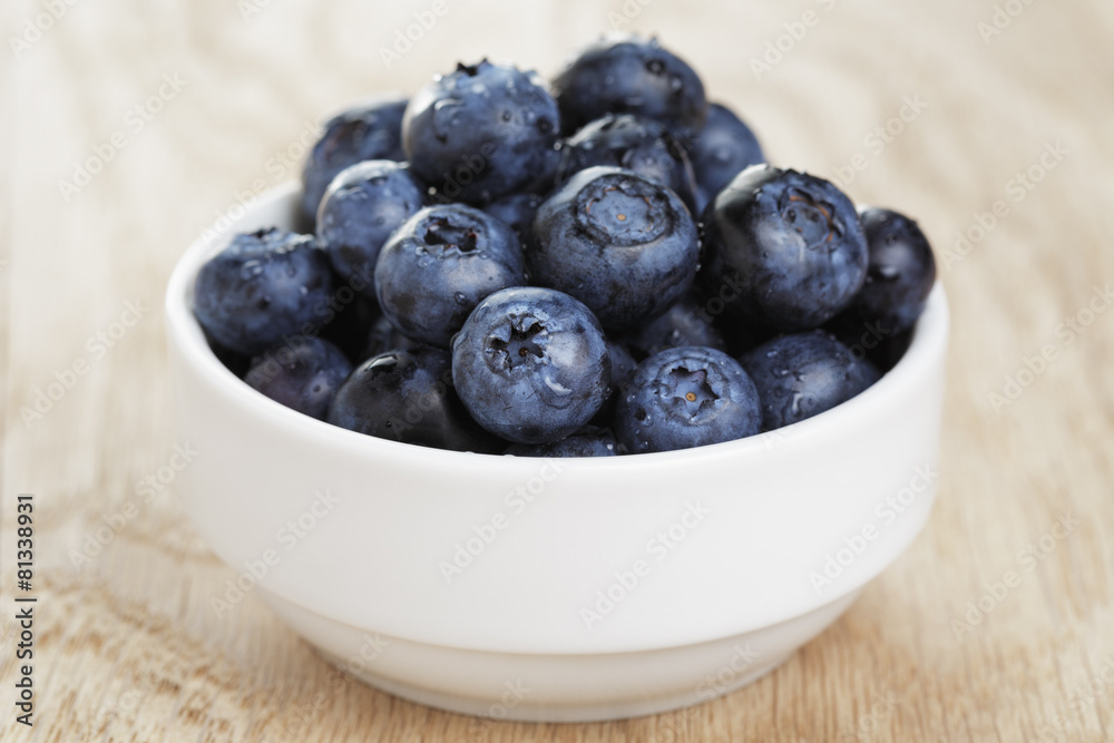 heap of fresh washed blueberries in white bowl on wood table heap of fresh washed blueberries in white bowl on wood table
