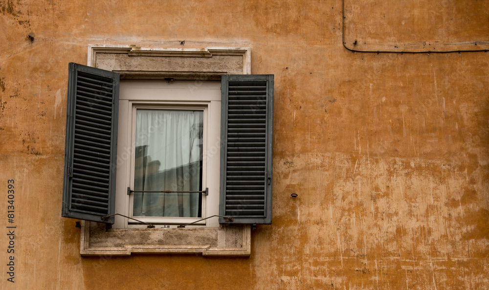 A Roman window, with shutters, set in an ochre coloured wall