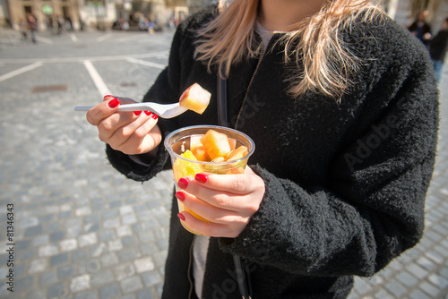 Woman eating fruit salad from lunch box in the city photo
