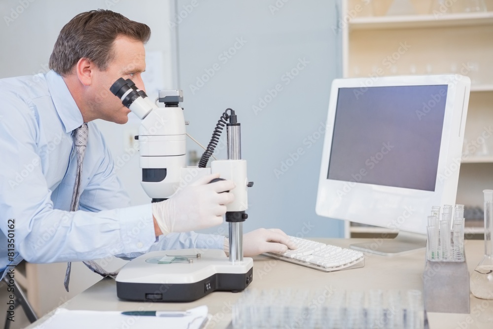 Scientist using computer and microscope Scientist using computer and microscope