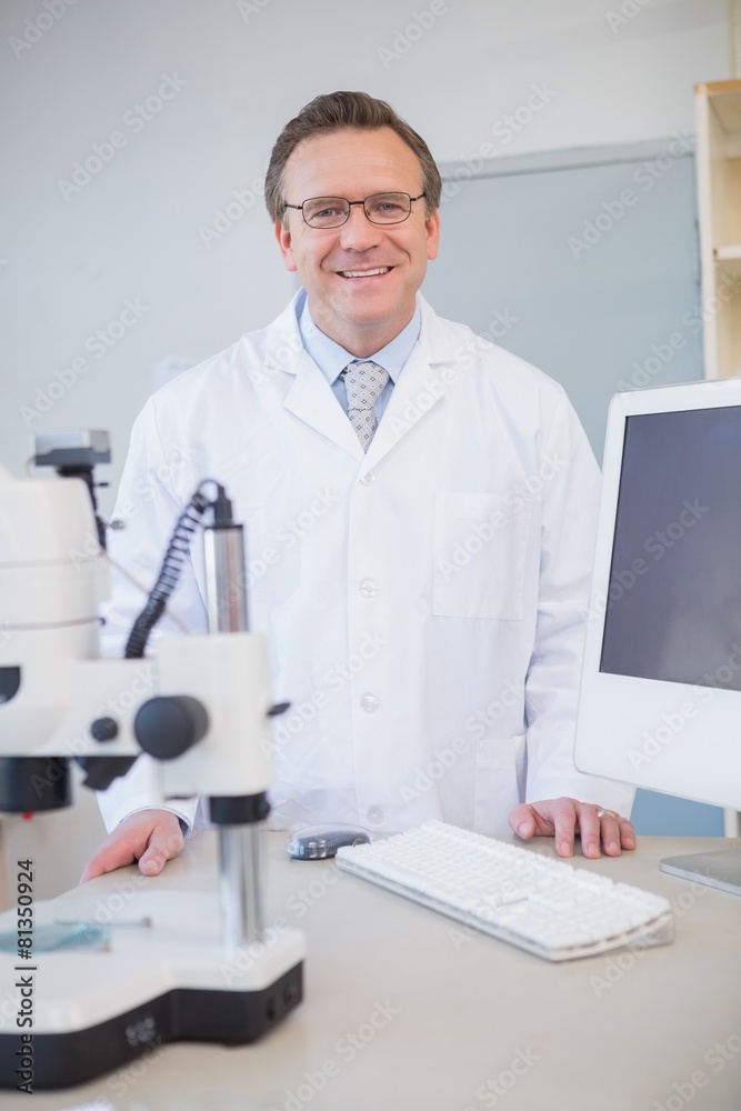Happy scientist looking at camera with hands on table