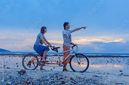 Young couple riding on the bicycle on the beach