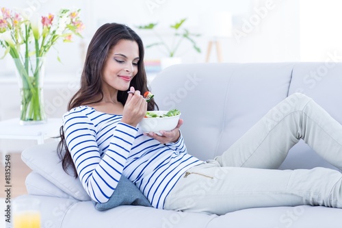 Smiling beautiful brunette eating salad