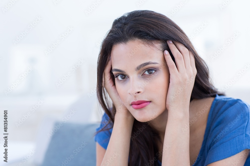 Thoughtful beautiful brunette sitting on the couch Thoughtful beautiful brunette sitting on the couch