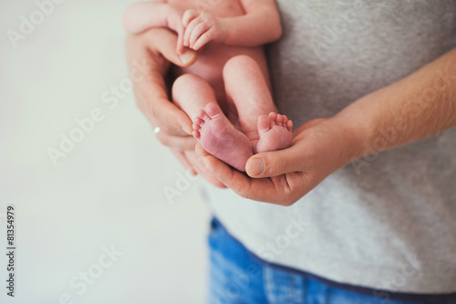 Newborn baby feet on father  hands, close-up