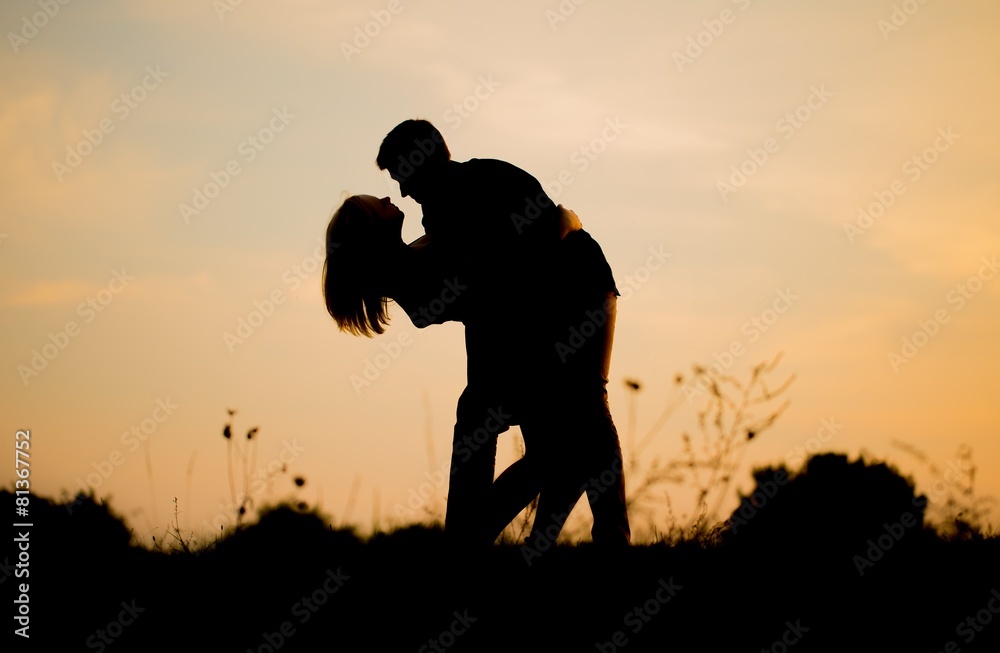 Silhouettes of hugging couple against the sunset sky.