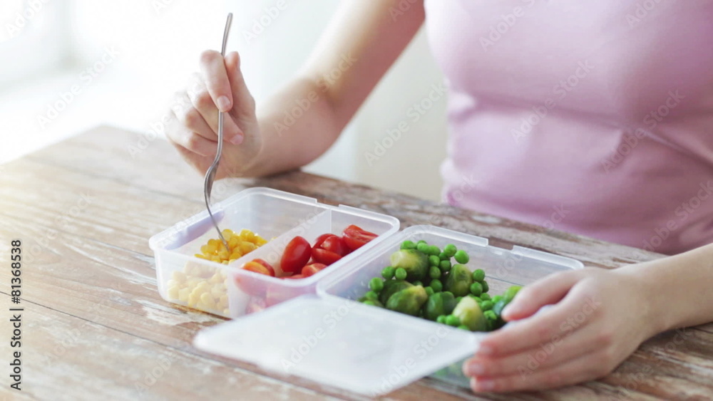 close up of woman eating vegetables from container close up of woman eating vegetables from container