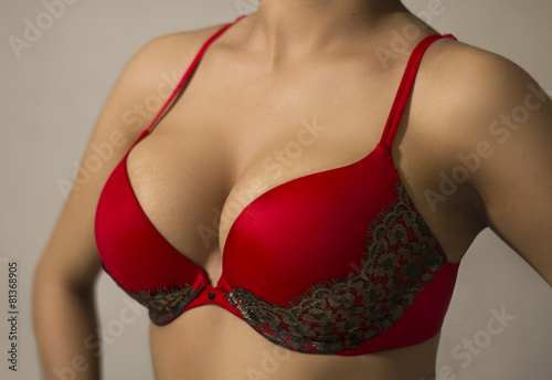 Woman wearing a red brassiere isolated on a gray background