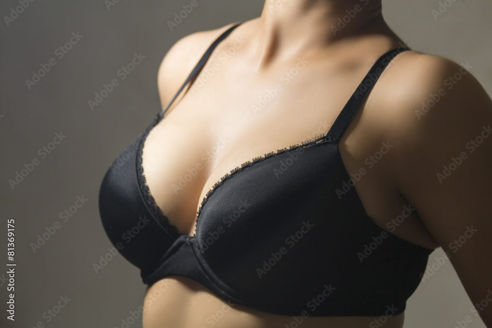 Fototapeta premium Woman wearing a black brassiere isolated on a gray background