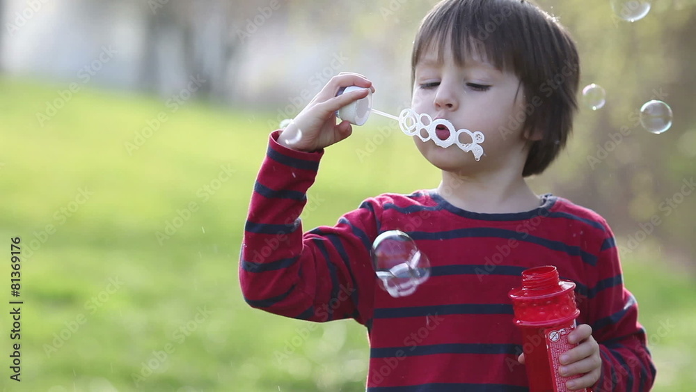 Cute little boy, playing with soap bubbles in the park Cute little boy, playing with soap bubbles in the park
