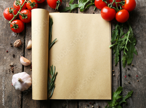 Open recipe book with fresh herbs, tomatoes and spices