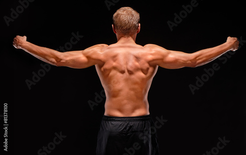 Rear view of sexy muscular sportsman with arms stretched out
